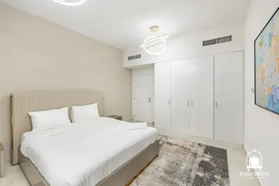 a white bedroom with a bed and white cabinets at Spacious 4BR Stay Sea JBR Views Sadaf 8 EB in Dubai