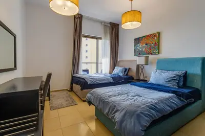 a bedroom with two beds and a table and a couch at Modern 2 BDR Apartment with Sea View Shams 1 JBR in Dubai
