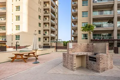 a picnic table and a grill in front of a building at Surrounded by Nature Near Internet & Media City in Dubai