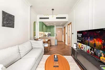 a living room with a white couch and a flat screen tv at Modern 1BR Apartments by Nestovia in JVC with Pool and City Views in Dubai
