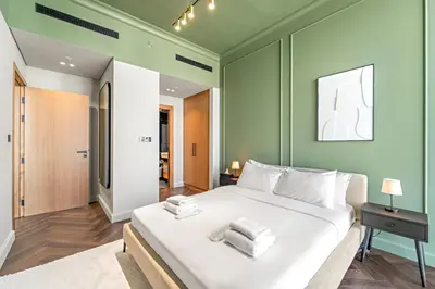 a bedroom with a large white bed with green walls at Modern 1BR Apartments by Nestovia in JVC with Pool and City Views in Dubai