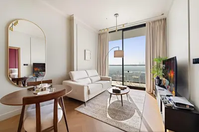 a living room with a white couch and a mirror at Modern 1BR Apartments by Nestovia in JVC with Pool and City Views in Dubai