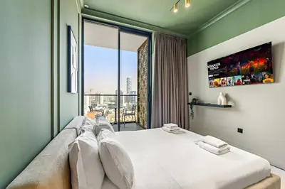 a bedroom with a large bed with a large window at Modern 1BR Apartments by Nestovia in JVC with Pool and City Views in Dubai