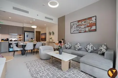 a living room with a couch and a table and a kitchen at Vogue Downtown Grande Signature Residences, near Dubai Mall and Burj Khalifa, Two-Bedroom Apartment with Large Balcony, Infinity Pool with Burj Khalifa View, Access to all Amenities in Dubai