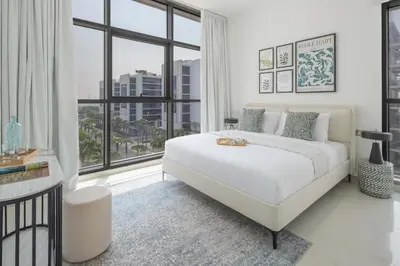 a white bedroom with a large bed and a large window at Frank Porter - Loreto 3 in Dubai