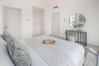 a white bedroom with a large bed with a mirror at Frank Porter - Loreto 3 in Dubai