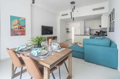 a dining room table with chairs and a blue couch at Frank Porter - Loreto 3 in Dubai