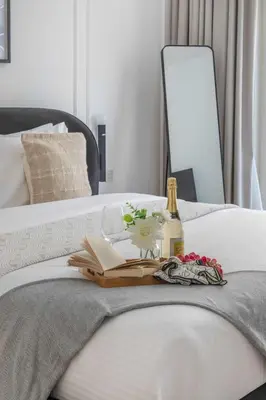 a tray with a bottle of wine and a book on a bed at Frank Porter - Bay Square 1 in Dubai