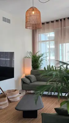 a living room with a green couch and a tv at Private 2BR Oasis with Jacuzzi, Massage Chair, PS5, Steps Away From Opera, Dubai Mall, Dubai Fountains in Dubai
