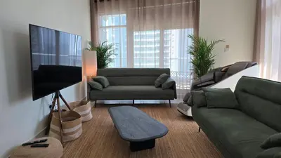 a living room with a couch and a tv at Private 2BR Oasis with Jacuzzi, Massage Chair, PS5, Steps Away From Opera, Dubai Mall, Dubai Fountains in Dubai