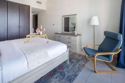 a bedroom with a bed and a blue chair at Frank Porter - Churchill Residence Tower 2 in Dubai