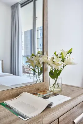 a table with a mirror and a vase with flowers at Frank Porter - Samana Park Views in Dubai
