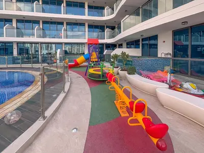 a large building with a pool with slides and a playground at Frank Porter - Samana Park Views in Dubai