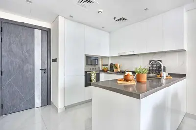 a kitchen with white cabinets and a counter top at Frank Porter - Samana Park Views in Dubai