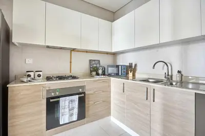 a kitchen with white cabinets and a sink and an oven at Frank Porter - The Bay in Dubai
