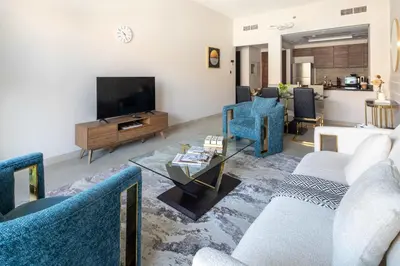 a living room with blue chairs and a television at Frank Porter - Eleganz 5 By Danube in Dubai