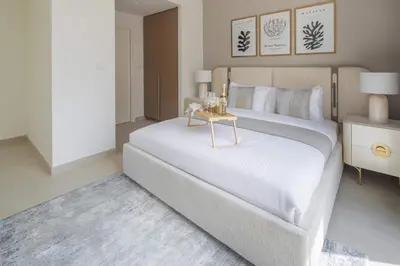 a bedroom with a large white bed with a side table at Frank Porter - Rosewater at Creek Beach 3 in Dubai