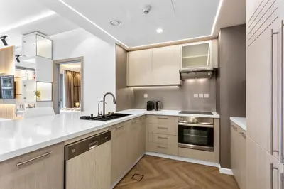 a kitchen with white counter tops and wooden cabinets at Stylish Stay 2 Bedroom Minutes from Burj Khalifa in Dubai