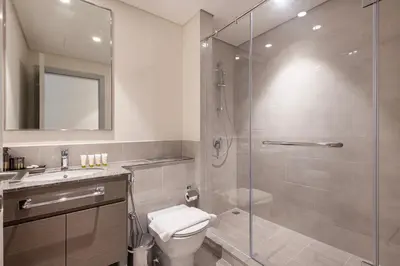a bathroom with a shower and a toilet and a sink at Forte Tower 2 - 3 Bedroom with Maid's Room Apartment - Allsopp & Allsopp in Dubai