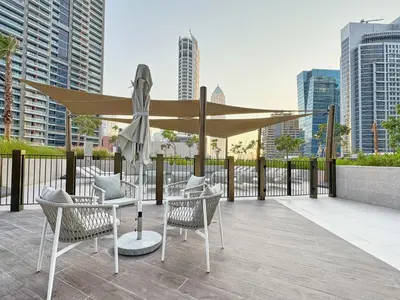 a patio with chairs and a large umbrella at Modern Studio in Business Bay with Pool, Gym & Canal View in Dubai