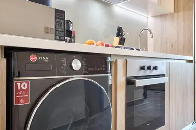 a kitchen with a washing machine under a counter at Modern Studio in Business Bay with Pool, Gym & Canal View in Dubai
