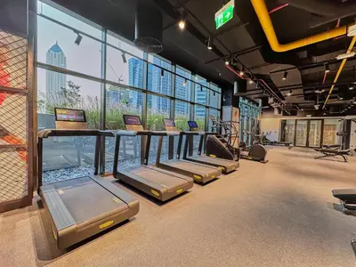 a gym with a row of treadmills and windows at Modern Studio in Business Bay with Pool, Gym & Canal View in Dubai