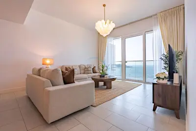 a living room with a couch and a large window at Beachfront Stay with Full Sea Views, Walking Distance to The Walk, JBR Beach, and Dubai Marina - La Vie, Jumeirah Beach Residence by Deluxe Holiday Homes in Dubai