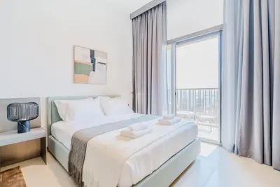 a white bedroom with a bed and a large window at TRPS - MAG EYE 970, MBR - Modern and Cozy Studio, Furnished, MBR Living in Dubai