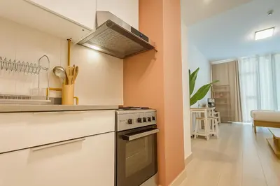 a kitchen with a stove top oven next to a table at Elegant Studio in JVC in Dubai