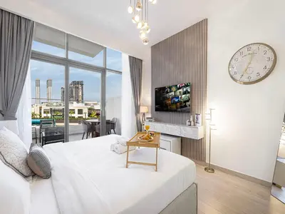 a bedroom with a large white bed and a clock at Livin' Holidays - Studio - Riviera Elegance in Dubai