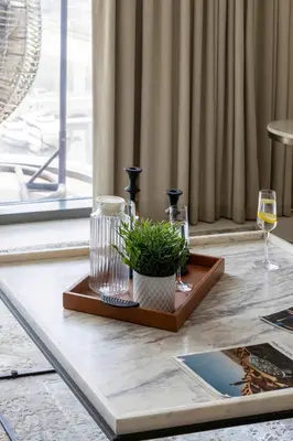 a table with a glass of wine and a plant at Frank Porter - Marina Vista Tower 1 in Dubai