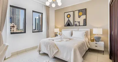 a bedroom with a large white bed and windows at Downtown 2BHK Iconic Burj Khalifa Views in Dubai