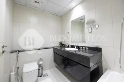 a bathroom with a sink and a toilet and a mirror at Bloomfields Cozy Stu Damac Ghalia Jvc in Dubai
