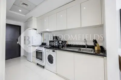 a kitchen with a sink and a washing machine at Bloomfields Cozy Stu Damac Ghalia Jvc in Dubai