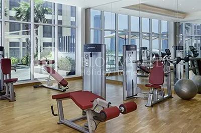 a gym with cardio equipment in a large room with windows at Bloomfields Cozy Stu Damac Ghalia Jvc in Dubai