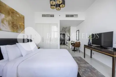 a white bedroom with a white bed and a television at Bloomfields Cozy Stu Damac Ghalia Jvc in Dubai