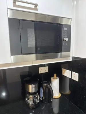 a microwave above a kitchen counter with a coffee maker at Cozy & Stylish Studio in Silicon Oasis in Dubai