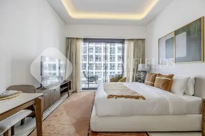 a white bedroom with a large bed and a tv at Bloomfields Lumière Stu Azizi Riviera in Dubai