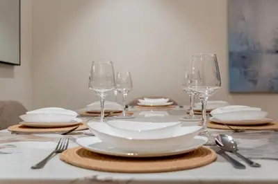a table with white plates and wine glasses on it at GuestReady - High-Floor 2BR | Canal and City View in Dubai
