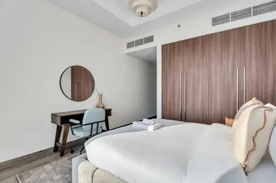 a bedroom with a bed and a desk and a mirror at GuestReady - High-Floor 2BR | Canal and City View in Dubai