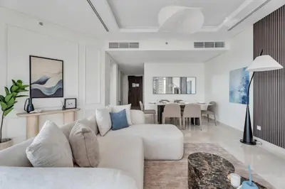 a white living room with a couch and a dining room at GuestReady - High-Floor 2BR | Canal and City View in Dubai