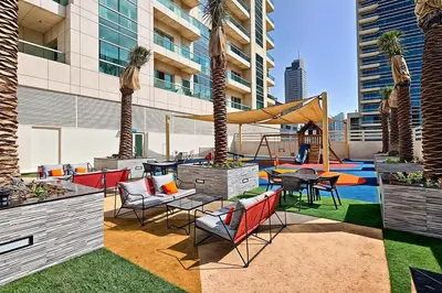 a patio with a playground with palm trees and chairs at 2b Stylish apart in JBR, near Beach&Marina Walk in Dubai