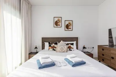 a white bedroom with a large white bed with blue towels at 2b Stylish apart in JBR, near Beach&Marina Walk in Dubai