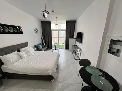 a bedroom with a bed and two tables in it at Binghatti Millennium Studio Apartment in Dubai