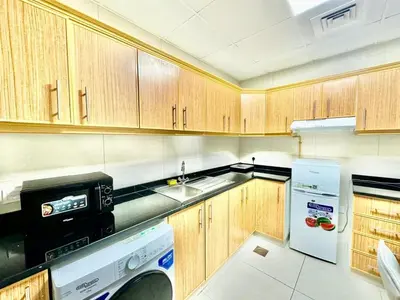 a small kitchen with wooden cabinets and a dishwasher at Perfect choice for a big family in Dubai