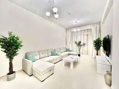 a white living room with a couch and a table at Not far from metro Spacious in Dubai