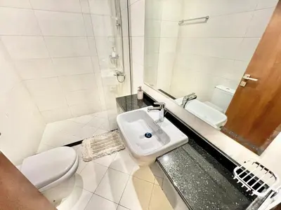 a white bathroom with a toilet and a sink at Not far from metro Spacious in Dubai