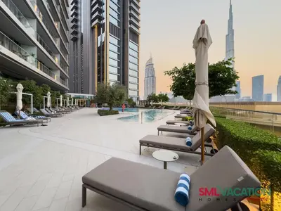 a row of lounge chairs with umbrellas and a pool at SML Vacation Homes at Vida Dubai Mall - Apartments with Burj Khalifa Views & access to the Dubai Mall in Dubai