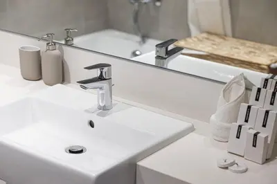 a white bathroom with a sink and a mirror at Elegant 1 Bedroom Apartment with Balcony & Lagoon in District One in Dubai