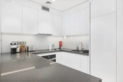 a kitchen with white cabinets and a gray counter top at Elegant 1 Bedroom Apartment with Balcony & Lagoon in District One in Dubai